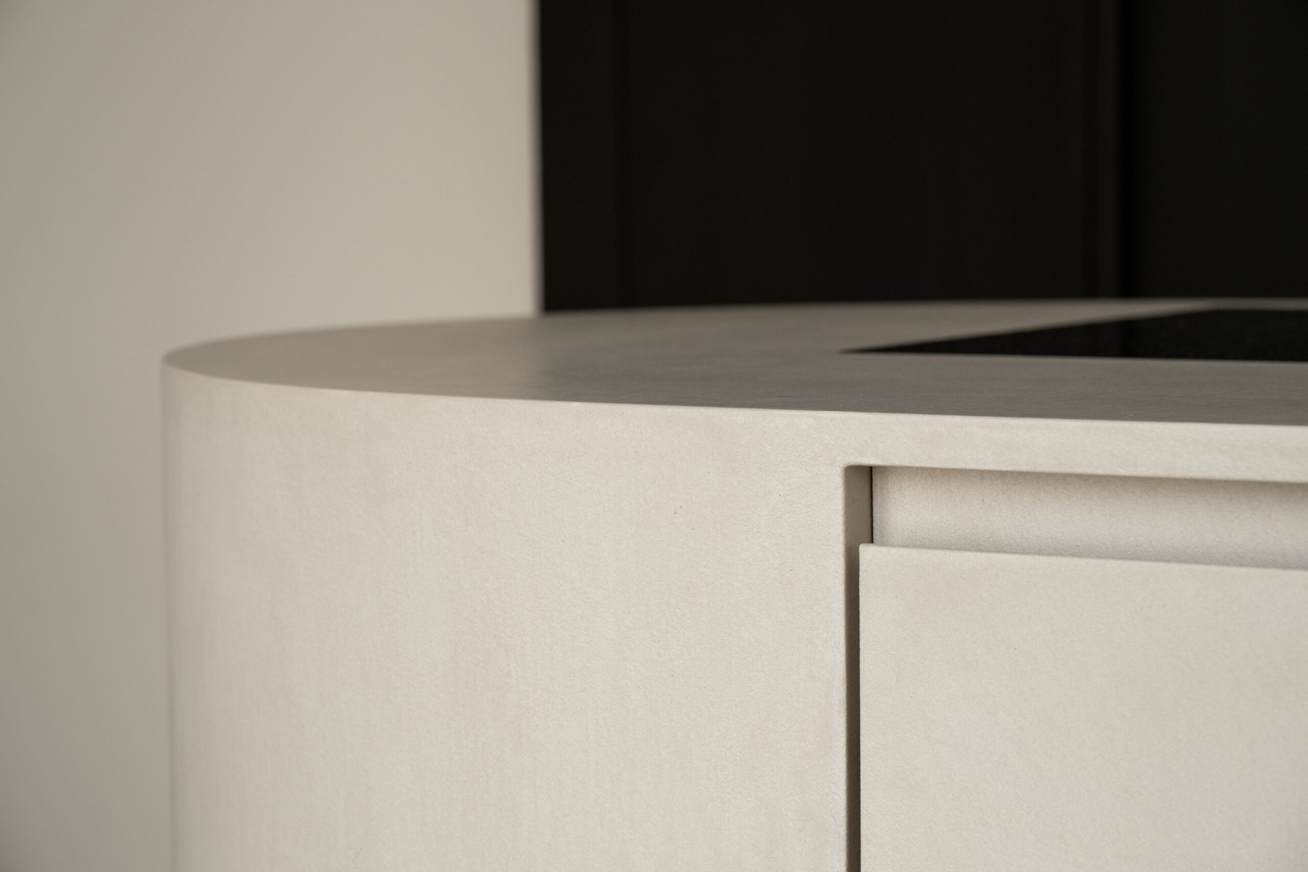 Close-up van de strakke afwerking en afgeronde hoek van een licht beige kookeiland in woning Uddel door Kardol Hout- en Interieurbouw