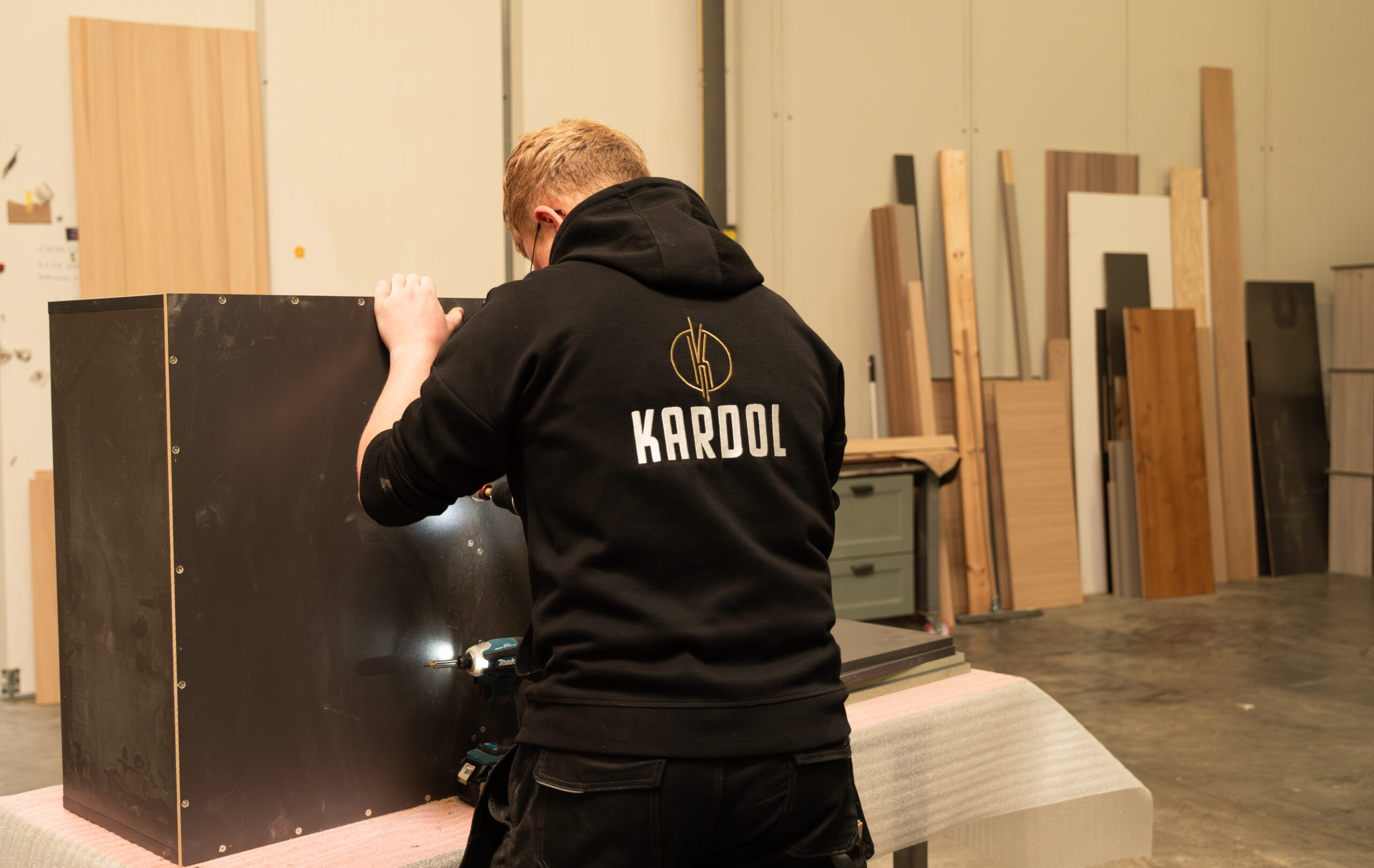Interieurbouwer in zwarte Kardol hoodie monteert een maatwerk kastmeubel in de houtbewerkingswerkplaats