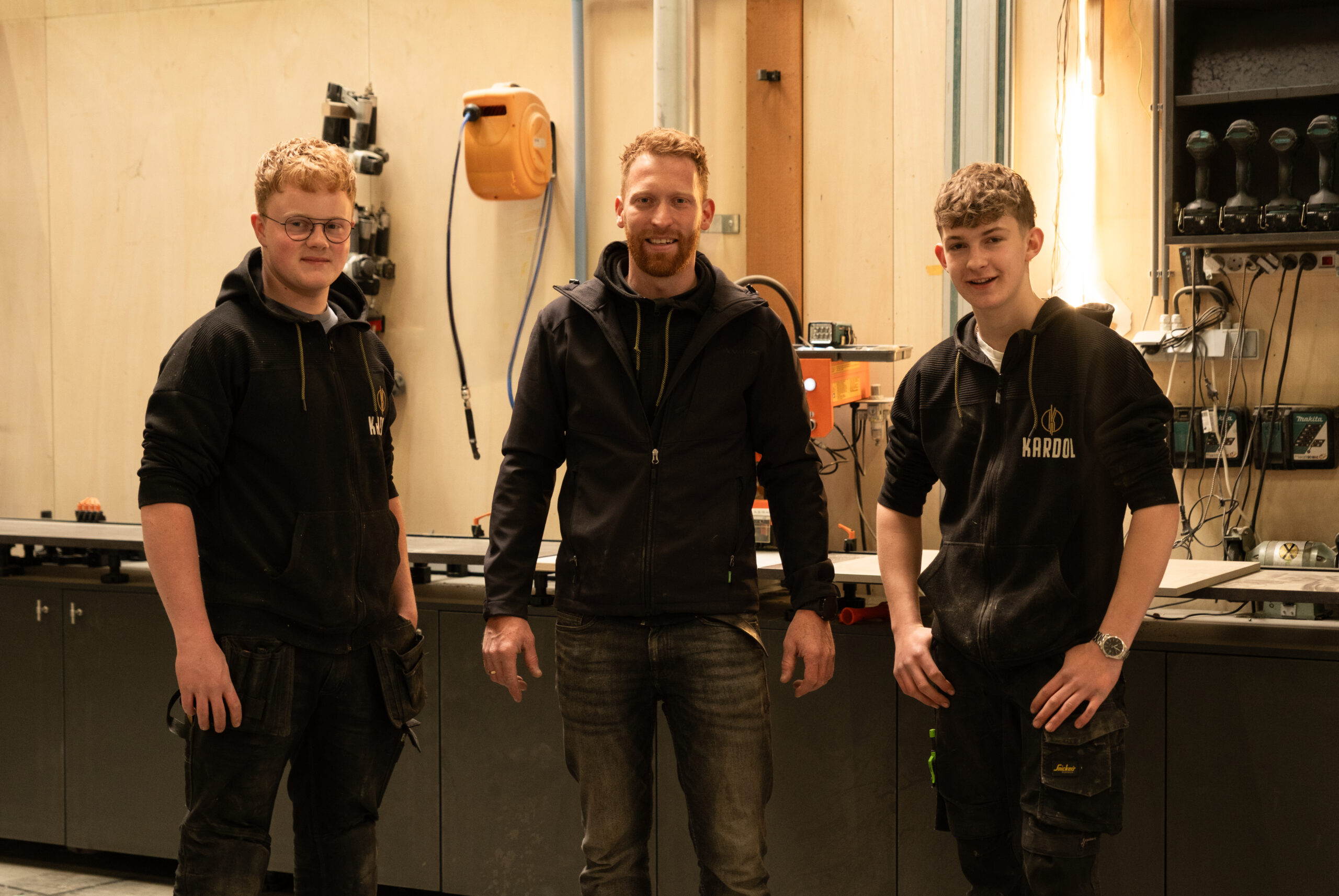 Groepsfoto van het vakbekwame team van Kardol Hout- en Interieurbouw in hun bedrijfskleding in de werkplaats