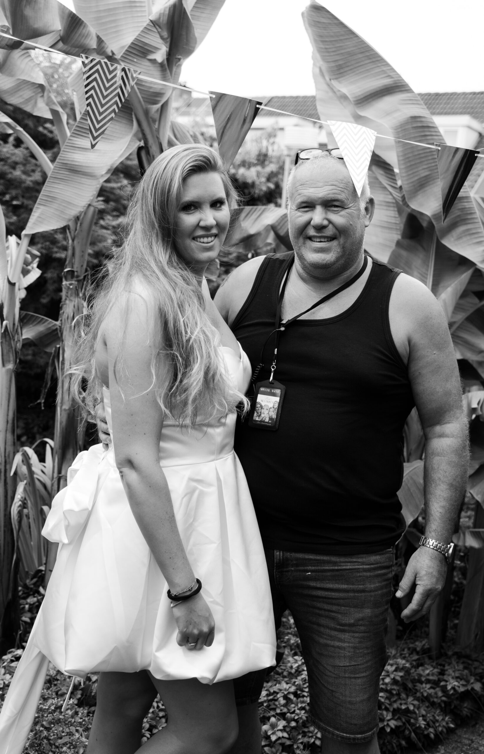 Zwart-wit foto van Anne in een witte jurk samen met een man onder feestelijke vlaggetjes tijdens haar bachelorette party