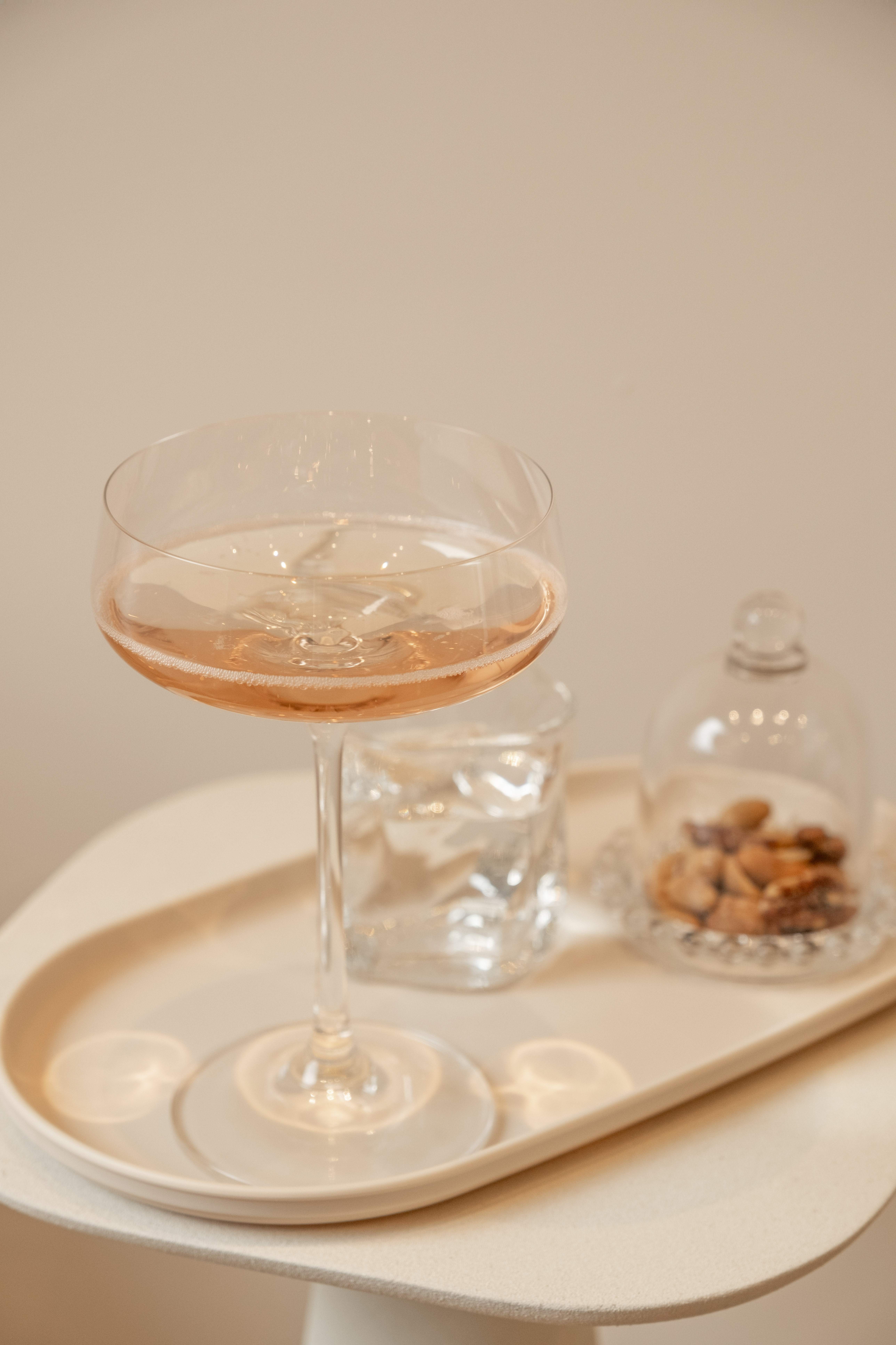 Elegante coupe met rosé bubbels en nootjes op een beige dienblad bij kapsalon Dari Tiga in Putten
