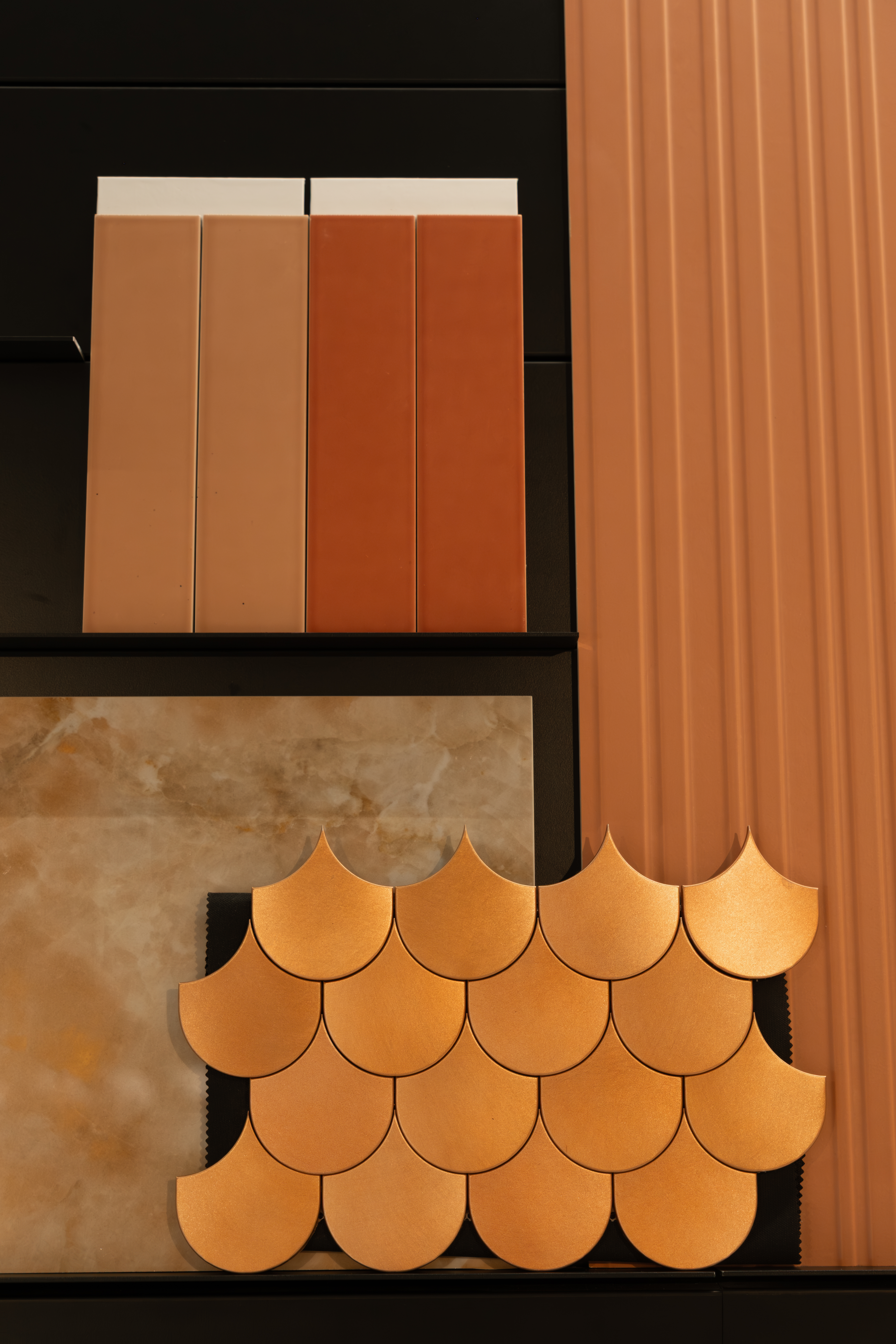 Detailopname van terrakotta wandtegels en gouden schubben mozaïek in de showroom van Berends Badkamers Woerden