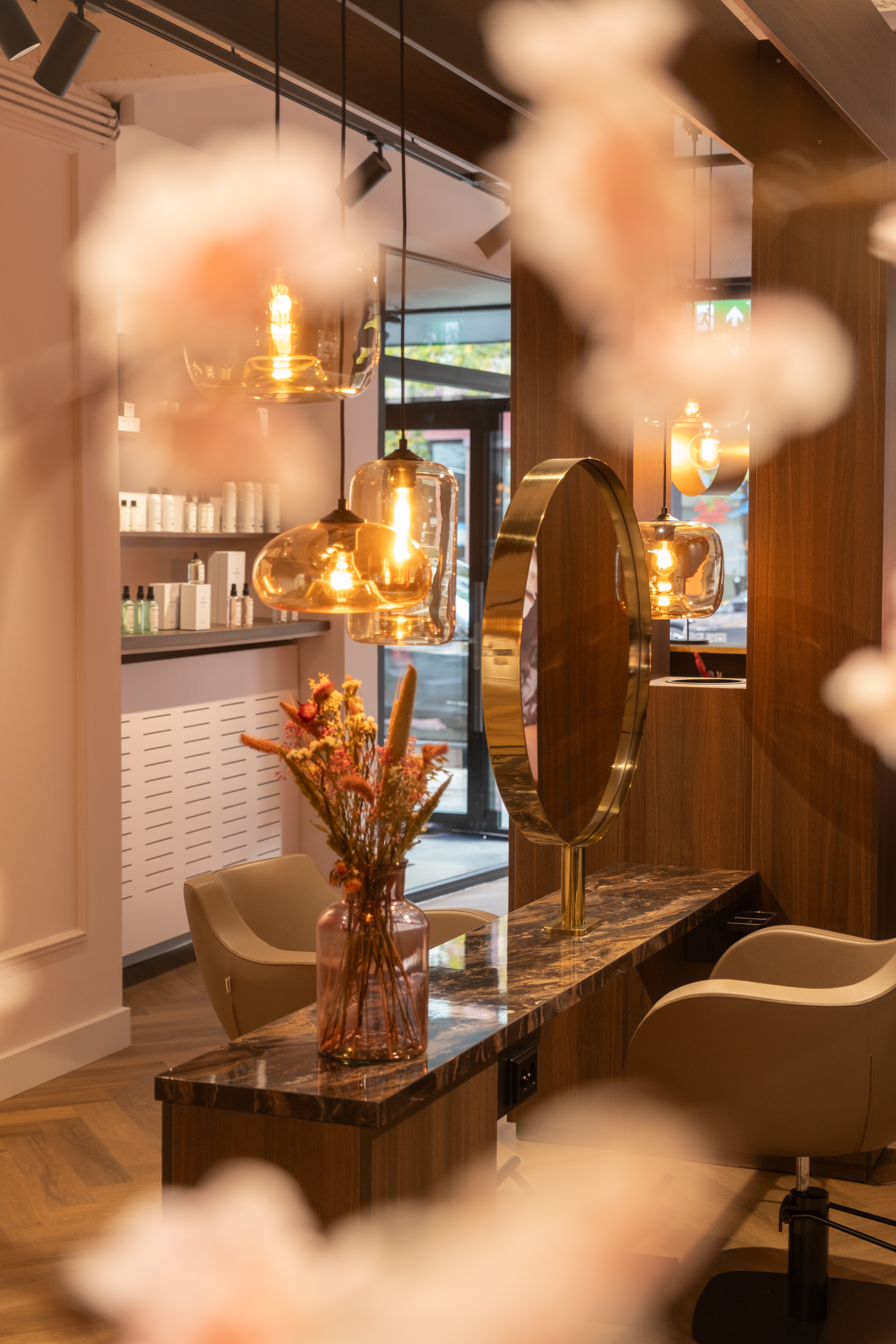 Sfeervol stylingstation bij Beauty by Roos Antwerpen met gouden spiegel, marmeren tafel en glazen hanglampen