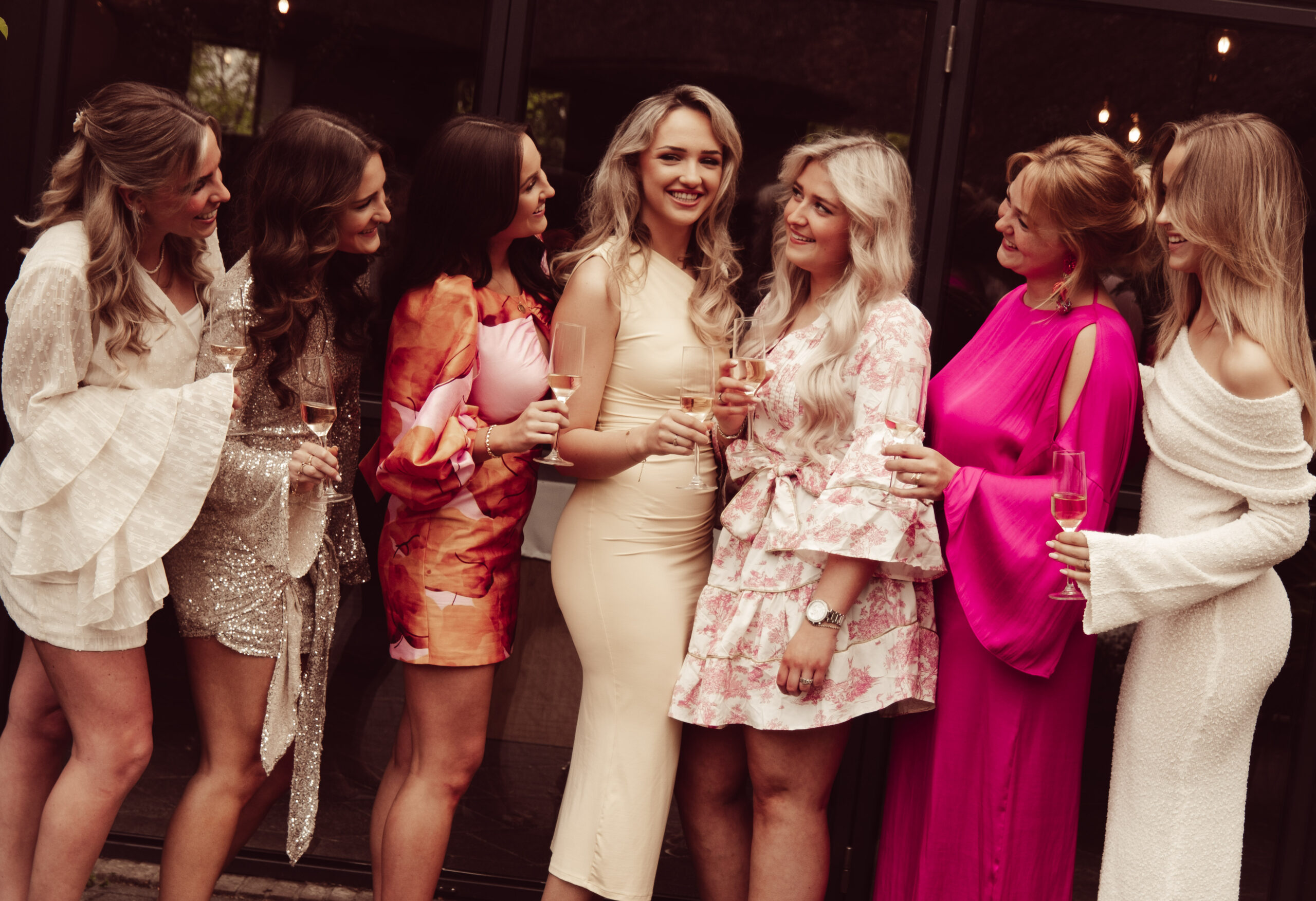 Groep stijlvol geklede vrouwen proost lachend met glazen champagne tijdens een feestelijk diner